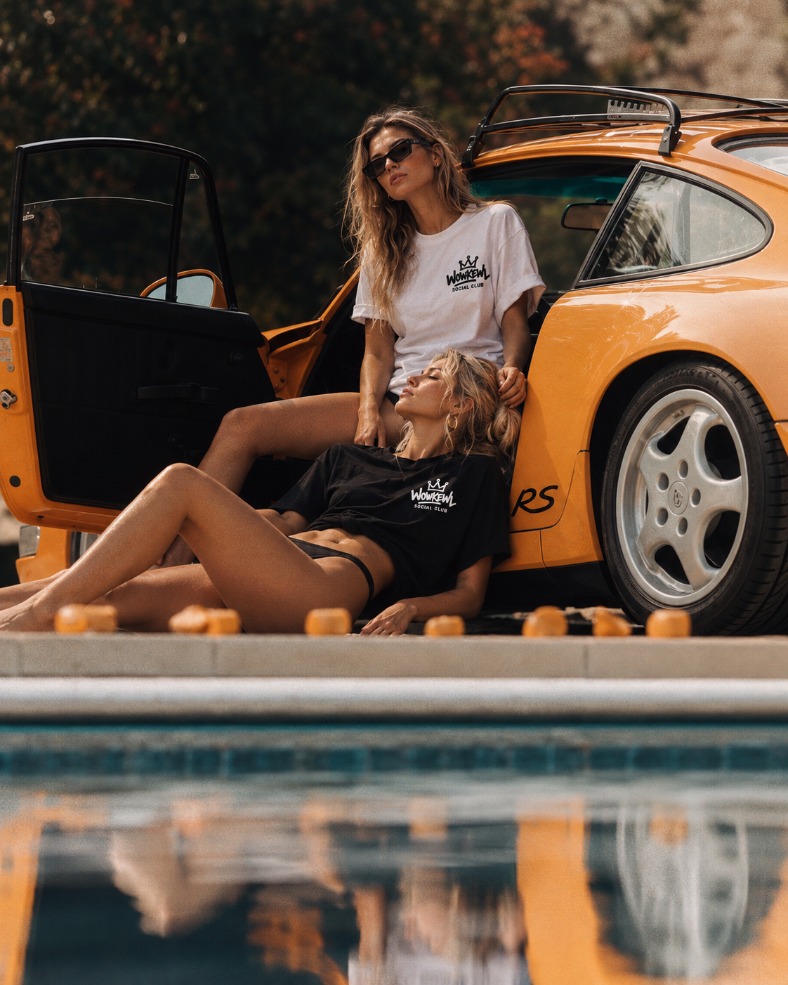 WOWKEWL Social Club – svart och vit T-shirt vid en orange bil